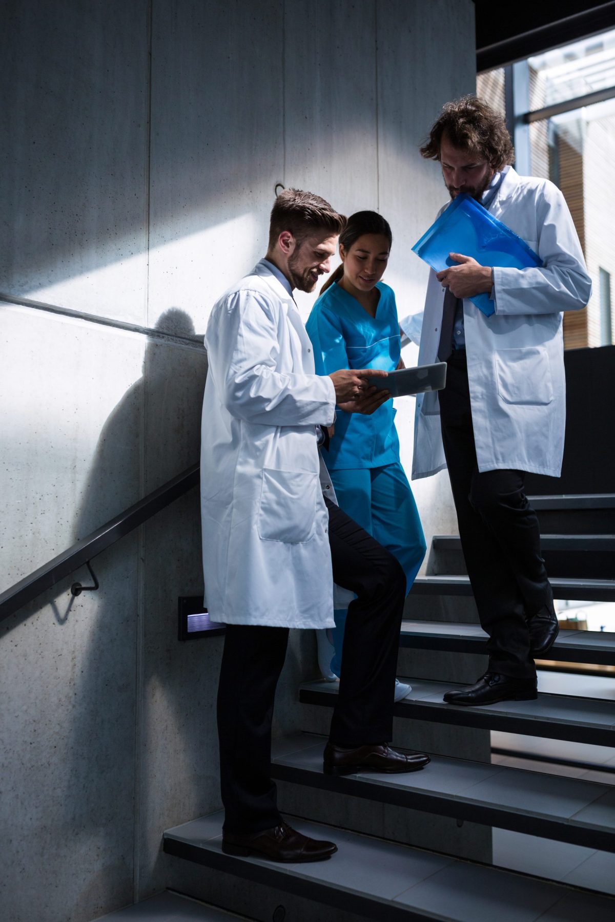 Doctors and nurse on stairs looking at digital tablet in hospital